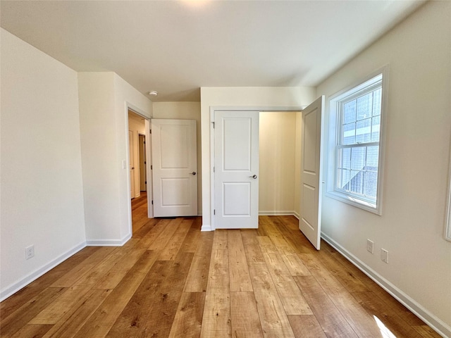 unfurnished bedroom with a closet, baseboards, and light wood-type flooring