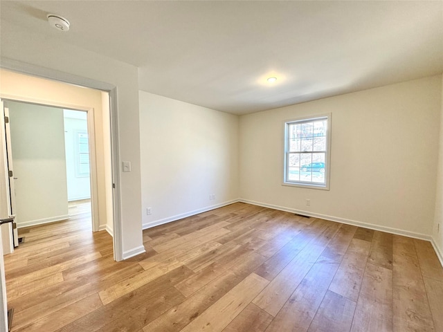 spare room featuring visible vents, wood-type flooring, and baseboards