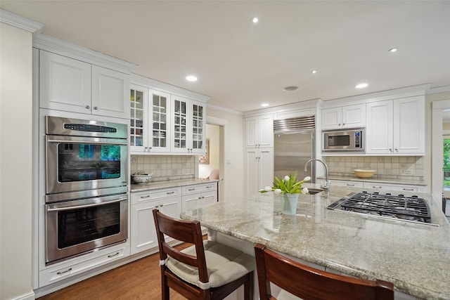 17 Eastwoods Rd, Pound Ridge, NY 10576 - kitchen with built in appliances, backsplash, white cabinetry, a breakfast bar area, and recessed lighting
