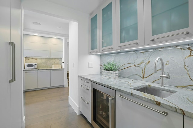 165 Valley Rd, New Rochelle, NY 10804 - bar featuring a sink, wine cooler, white microwave, light wood-style flooring, and decorative backsplash