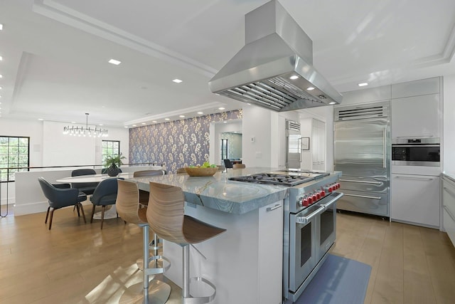 165 Valley Rd, New Rochelle, NY 10804 - kitchen with light wood-style flooring, a breakfast bar, island exhaust hood, and high quality appliances