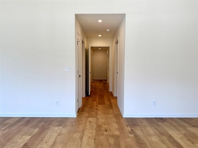 corridor featuring baseboards, light wood-type flooring, and recessed lighting