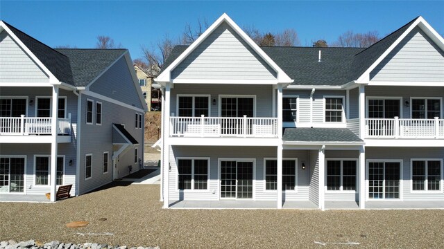 back of house with a shingled roof and a balcony