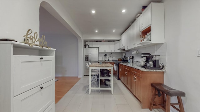 kitchen featuring recessed lighting, stainless steel appliances, open shelves, light stone countertops, and tasteful backsplash