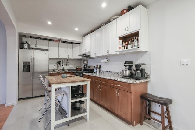 kitchen featuring under cabinet range hood, backsplash, appliances with stainless steel finishes, and wooden counters