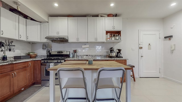 kitchen featuring under cabinet range hood, recessed lighting, backsplash, and gas range
