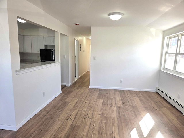 134-15 160th St, Jamaica, NY 11434 - spare room with a baseboard heating unit, wood finished floors, baseboards, and vaulted ceiling