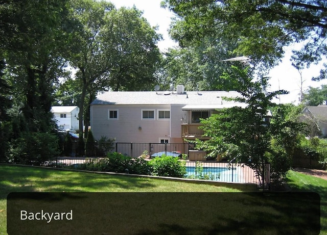 back of property with a fenced in pool, a yard, and fence