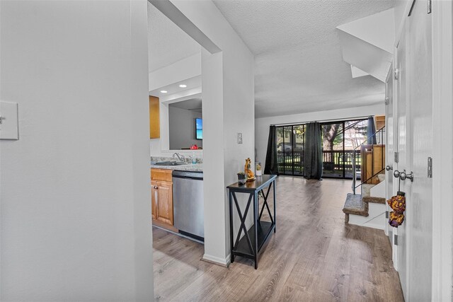 interior space featuring light wood finished floors, a textured ceiling, a sink, baseboards, and stairs