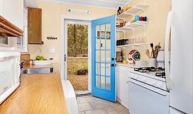 kitchen featuring white appliances, open shelves, white cabinets, light countertops, and a sink