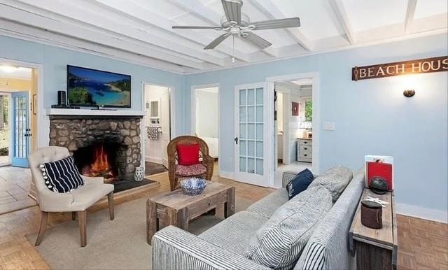 living area with a fireplace, a ceiling fan, french doors, baseboards, and beam ceiling