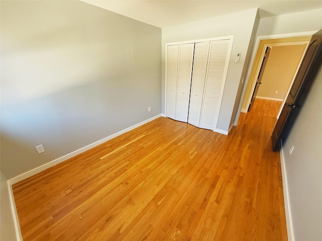 unfurnished bedroom featuring a closet, light wood-style floors, and baseboards
