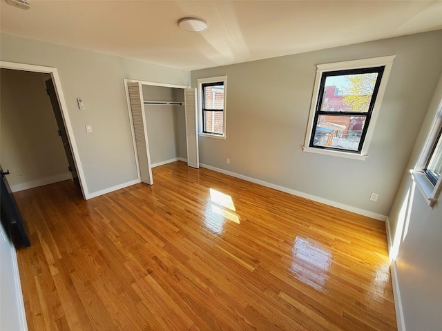 unfurnished bedroom with baseboards, wood finished floors, and multiple windows