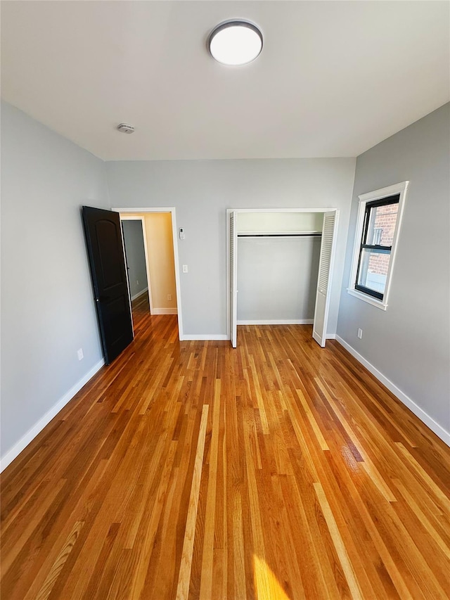 unfurnished bedroom featuring baseboards, light wood-style floors, and a closet