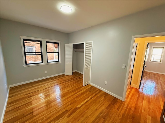 unfurnished bedroom featuring a closet, baseboards, and light wood-type flooring