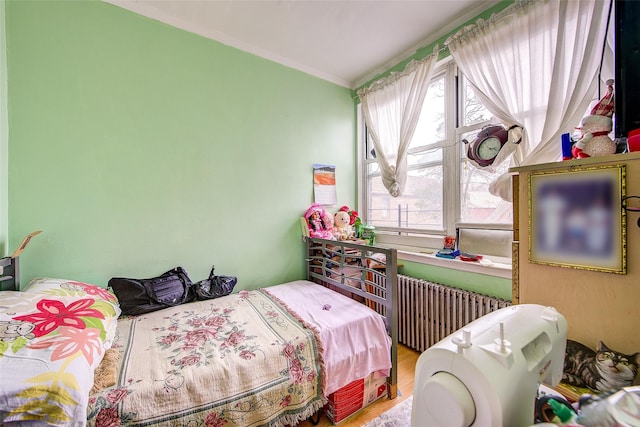 bedroom with crown molding, radiator, wood finished floors, and multiple windows