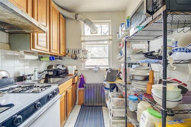 kitchen with white range with gas stovetop, radiator, plenty of natural light, and under cabinet range hood