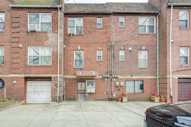 rear view of house with an attached garage, driveway, and brick siding