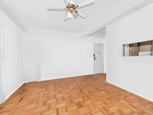 spare room featuring beamed ceiling, a ceiling fan, and a textured ceiling