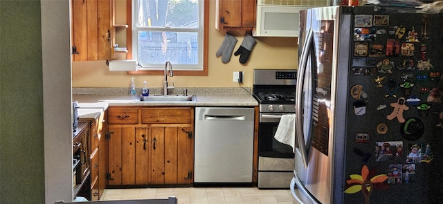 kitchen featuring a sink, light countertops, appliances with stainless steel finishes, and brown cabinets