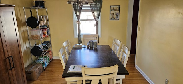 dining space featuring wood finished floors, an inviting chandelier, and baseboards