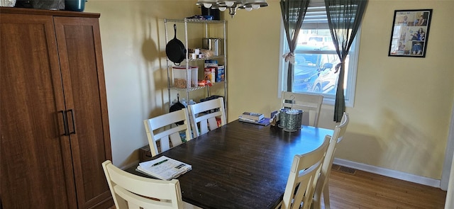 dining space with wood finished floors, an inviting chandelier, and baseboards