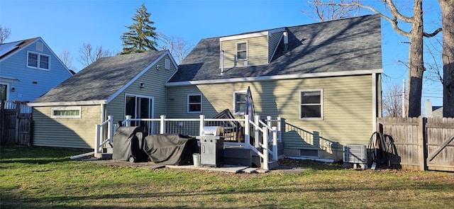 back of property featuring a deck, central air condition unit, fence, and a lawn