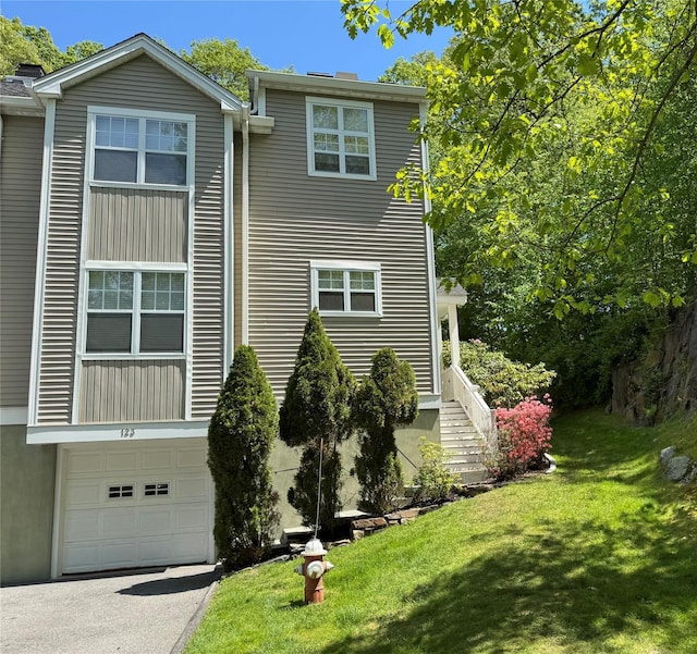 view of side of property featuring a garage, a yard, and driveway