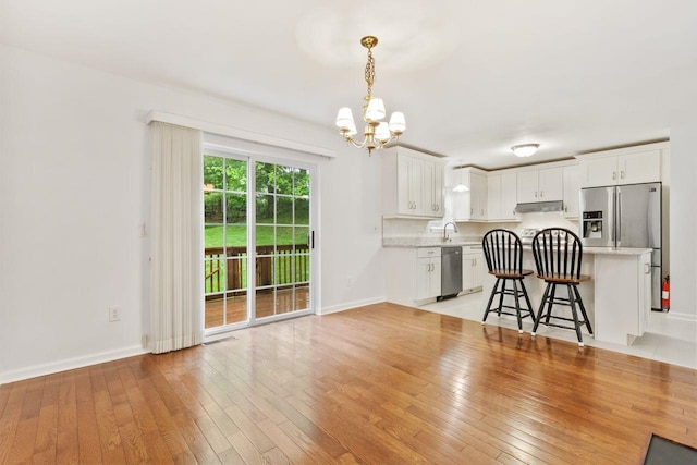 living area featuring a chandelier, light wood-type flooring, and baseboards