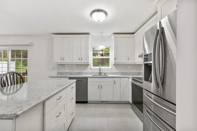 kitchen with stainless steel appliances, a sink, tasteful backsplash, and white cabinetry