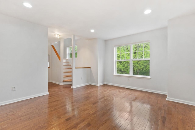 unfurnished room featuring healthy amount of natural light, wood finished floors, stairway, baseboards, and recessed lighting