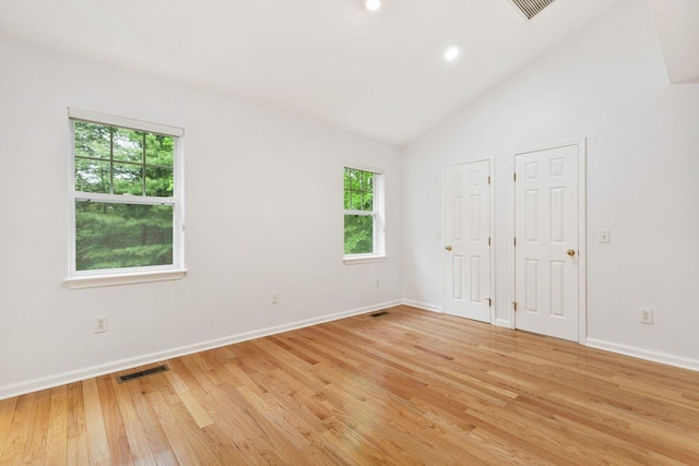 unfurnished bedroom featuring baseboards, light wood-type flooring, vaulted ceiling, multiple closets, and recessed lighting