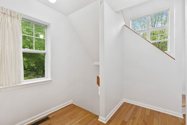 stairs with healthy amount of natural light, wood finished floors, and baseboards