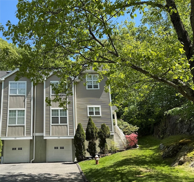 view of home's exterior with a garage, a lawn, and driveway