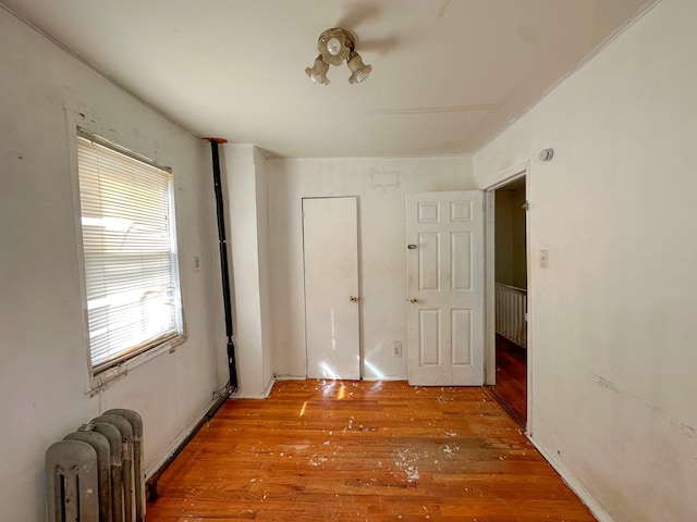 unfurnished bedroom featuring radiator and wood finished floors