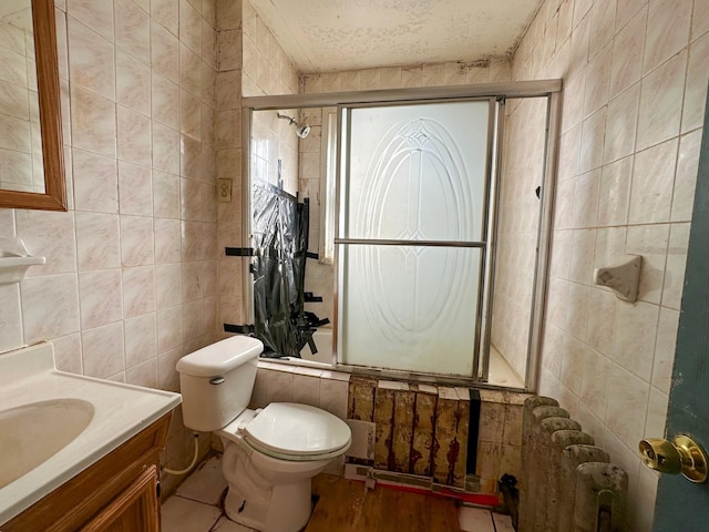 full bath featuring a textured ceiling, vanity, toilet, tiled shower / bath combo, and tile walls