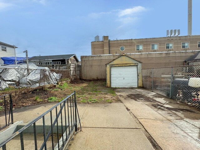 garage featuring concrete driveway and fence