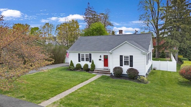 view of front of home with roof with shingles, fence, a chimney, and a front yard