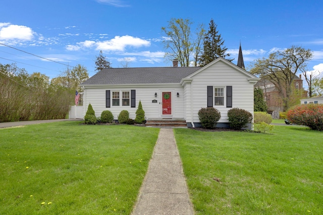 view of front of property featuring a shingled roof, a front yard, and a chimney