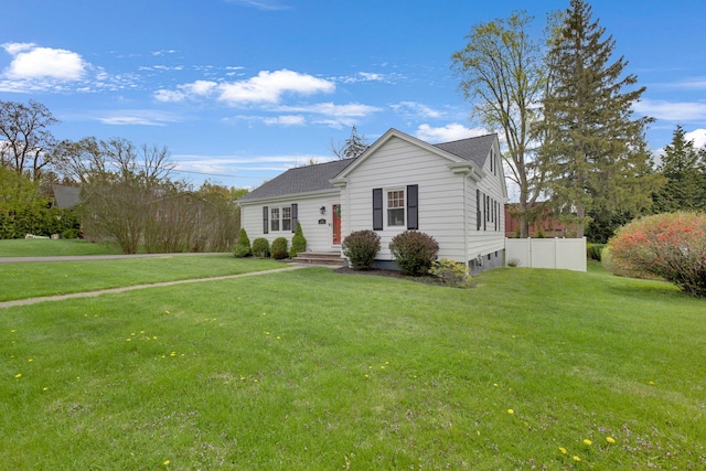 view of front facade featuring roof with shingles, fence, and a front yard