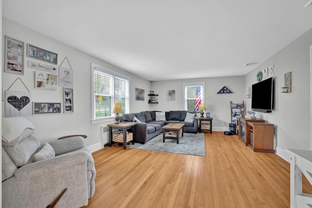 living area featuring visible vents, light wood finished floors, and baseboards