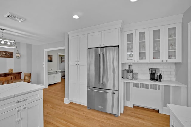 kitchen featuring visible vents, radiator, high end fridge, recessed lighting, and white cabinets