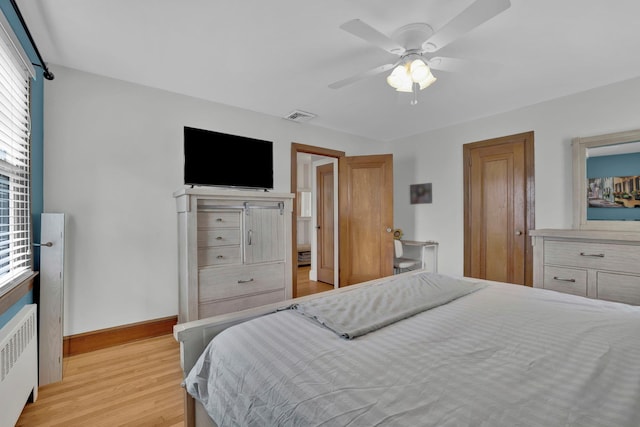 bedroom with visible vents, radiator, baseboards, light wood-style floors, and a ceiling fan