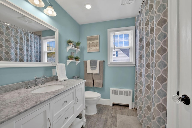 bathroom featuring toilet, a healthy amount of sunlight, radiator, and vanity