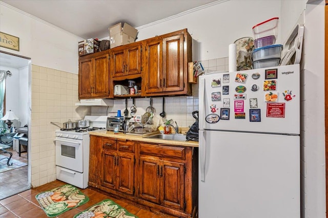 kitchen featuring a sink, light countertops, under cabinet range hood, tile patterned floors, and white appliances