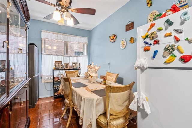 dining room with a ceiling fan and dark tile patterned flooring