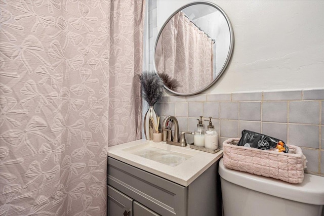bathroom with toilet, vanity, and decorative backsplash