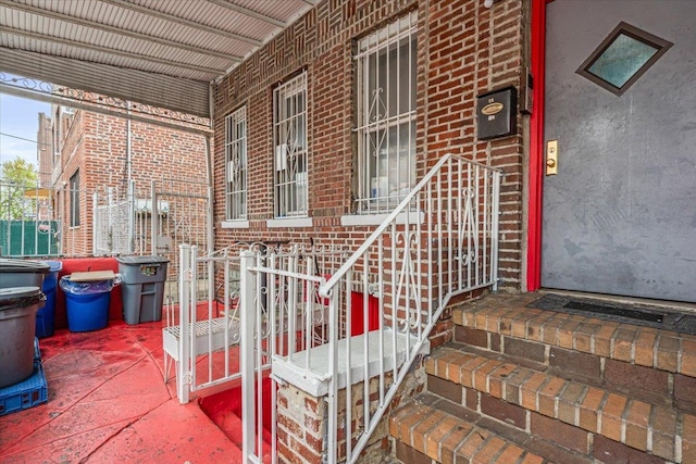 doorway to property with a porch and brick siding