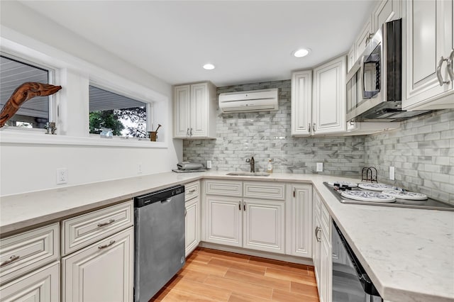 kitchen featuring appliances with stainless steel finishes, a wall unit AC, a sink, tasteful backsplash, and white cabinets
