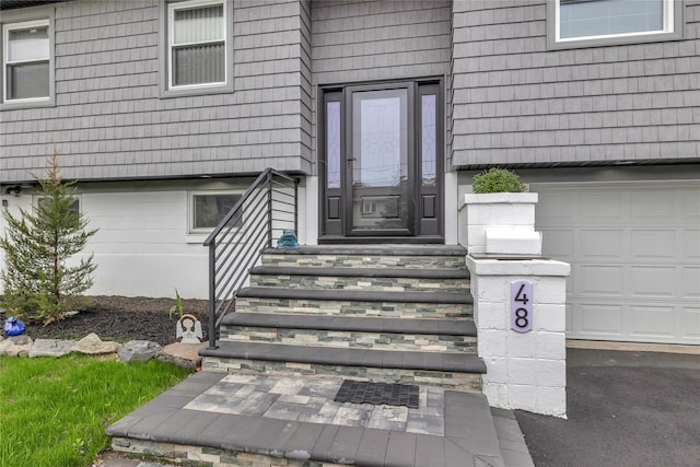 entrance to property featuring mansard roof and an attached garage